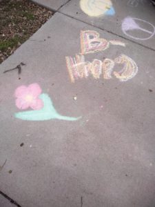 concrete sidewalk with child's drawing of single flower and "B-happy".